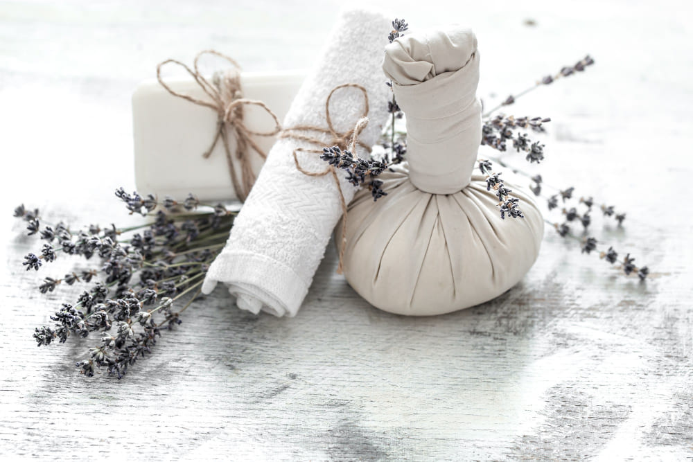 Folded clean laundry with sprigs of lavender and essential oil bottles on top